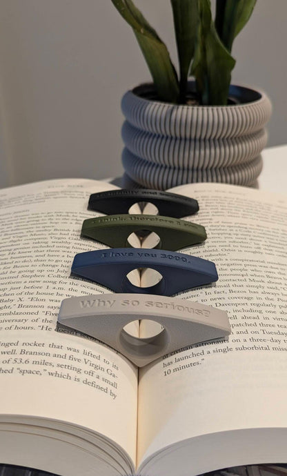 Image displaying an assortment of colorful page holders with unique text designs, with an ivory white Astria planter elegantly positioned in the background for a minimalist touch.